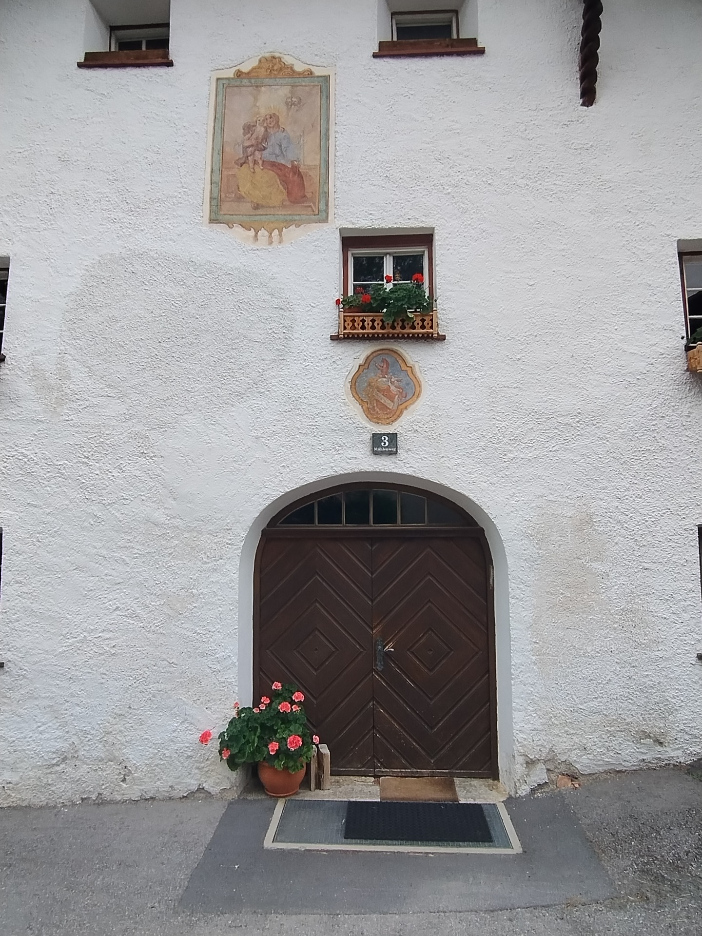 Historisk hus i Fiss, Tyrol, med håndmalet familievåbenskjold over døren og facadeudsmykning.
